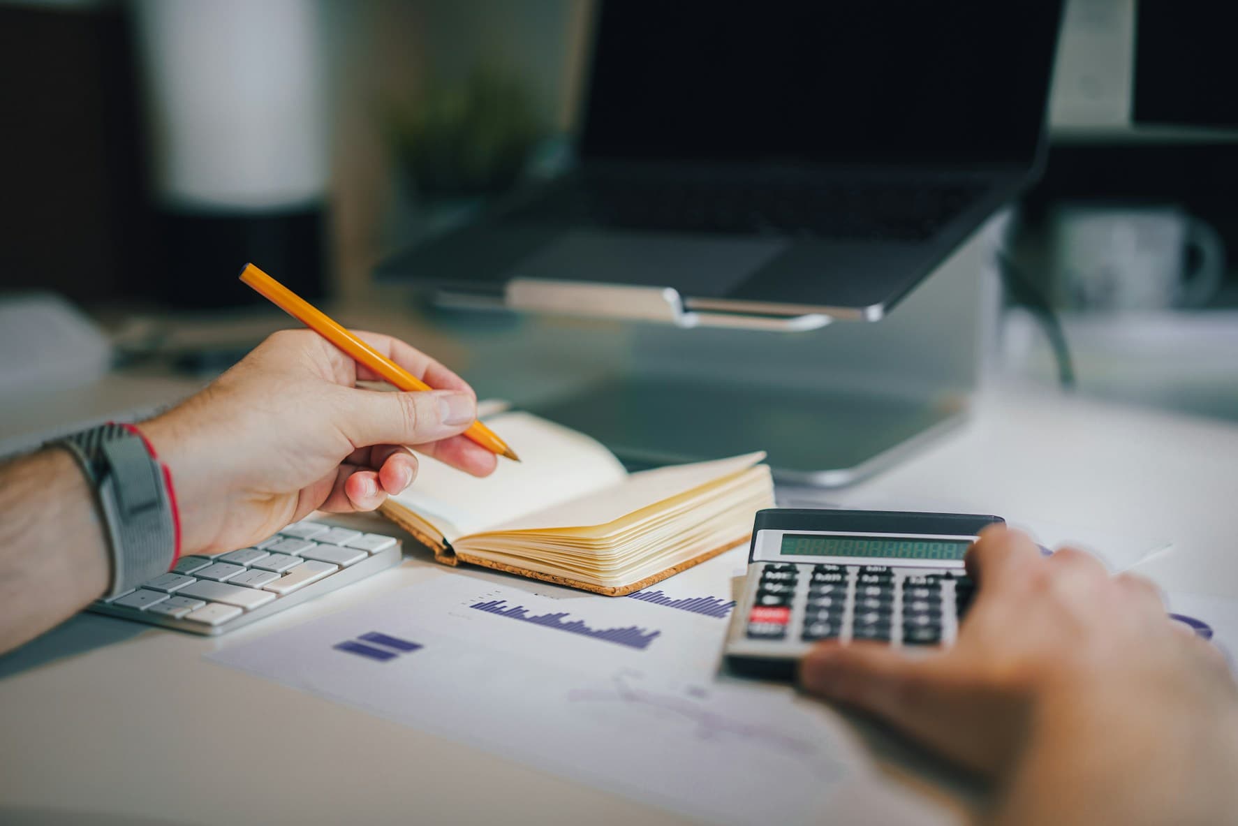 Writing reporting deadlines in a notebook beside a calculator